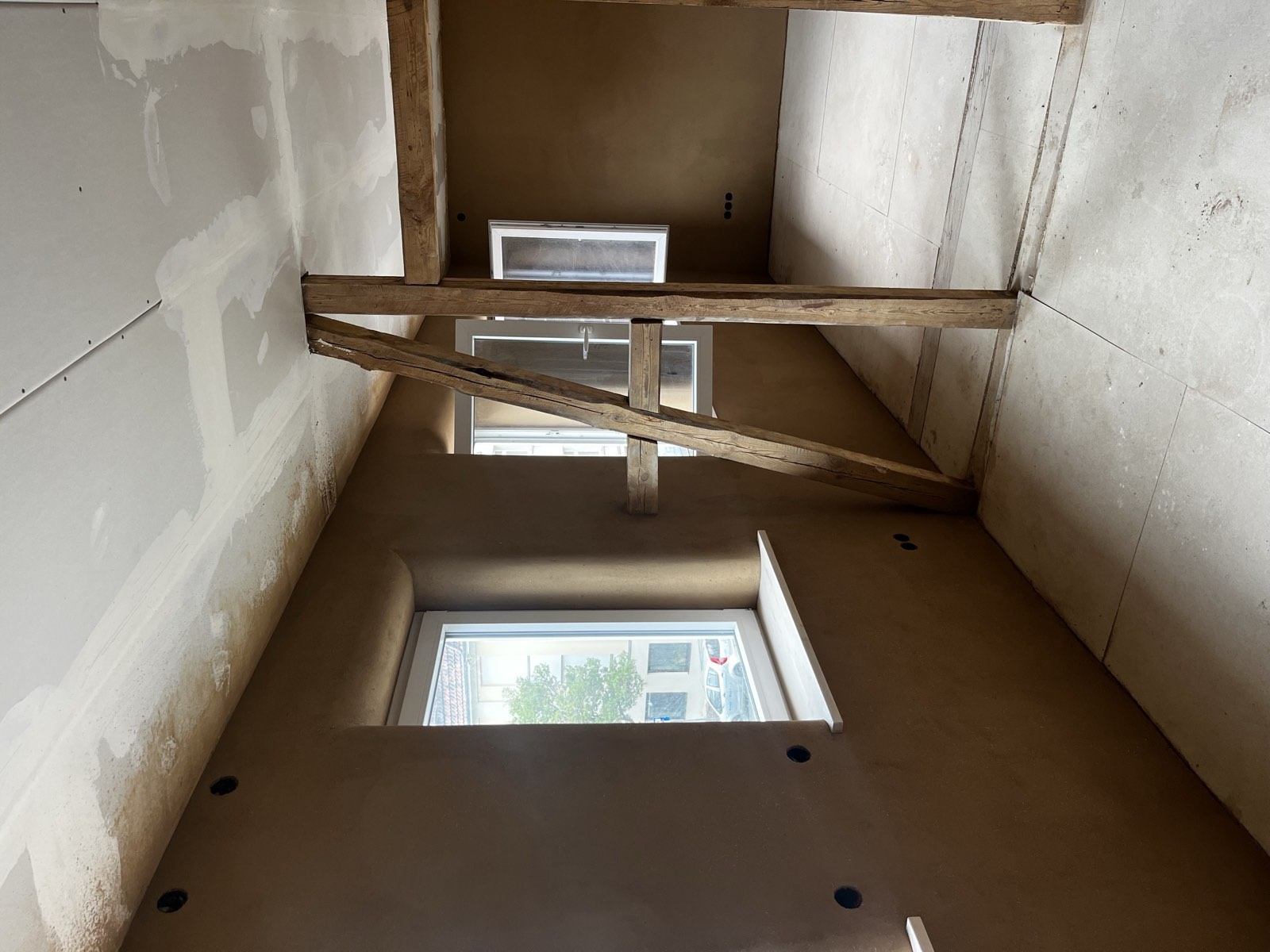 Lehmputz-Innenwand im Treppenhaus, warmer Braunton, sichtbarer Holzbalken, fertig
