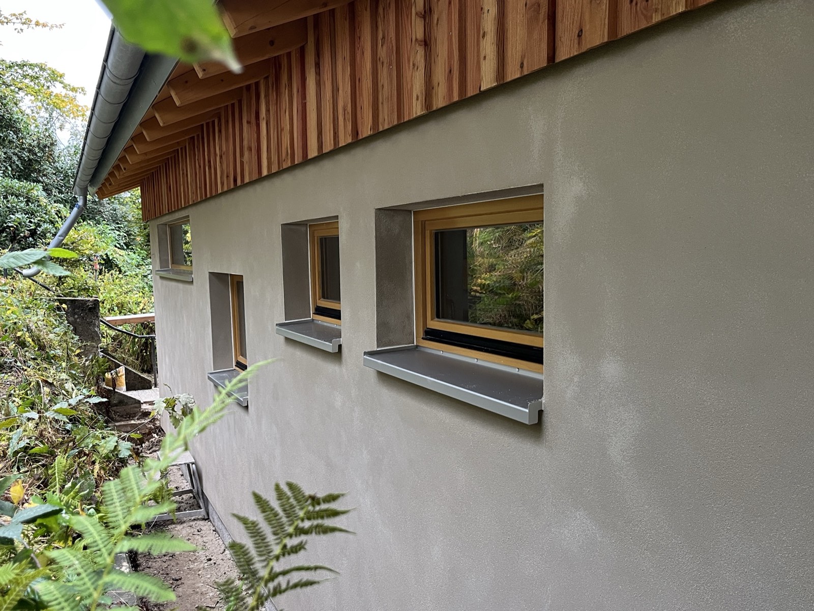 Holzhaus im Wald: Außenfassade mit Holzschalung und Holzfaserdämmung im Rohbauzustand