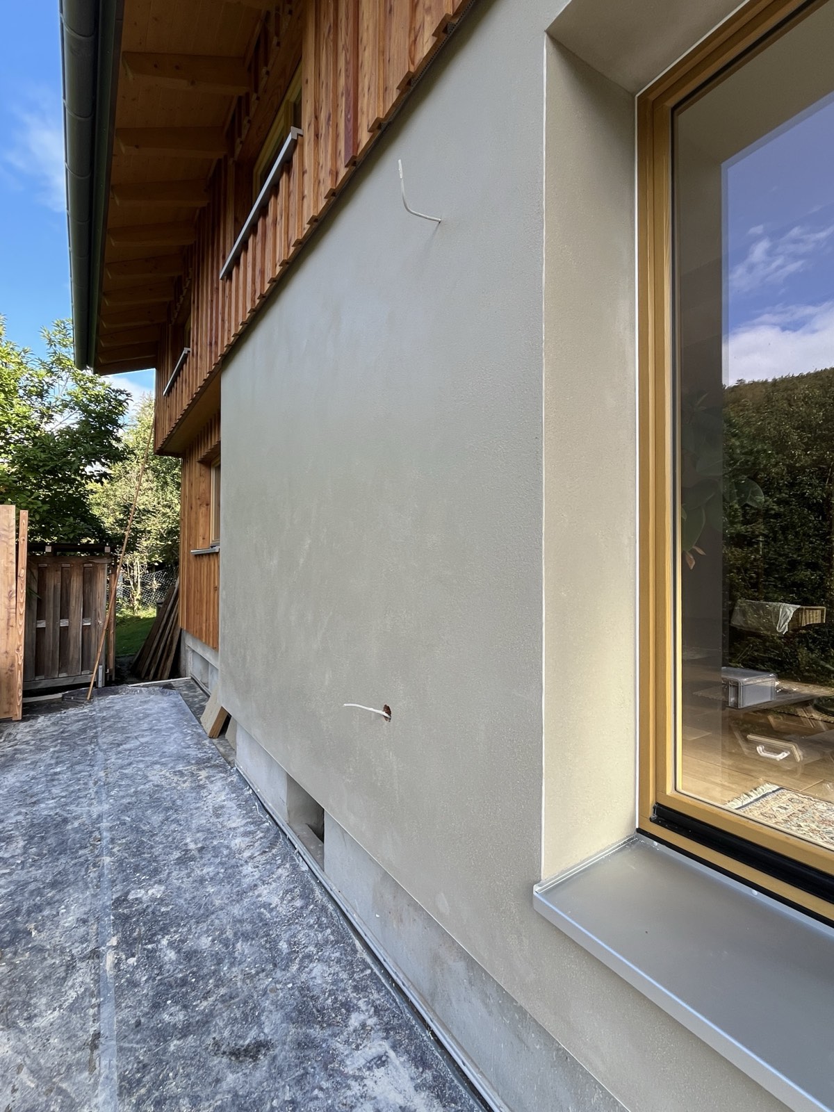 Kalkputzfassade fertig: heller Ton, Fenster mit Holzrahmen, Reflexion im Glas