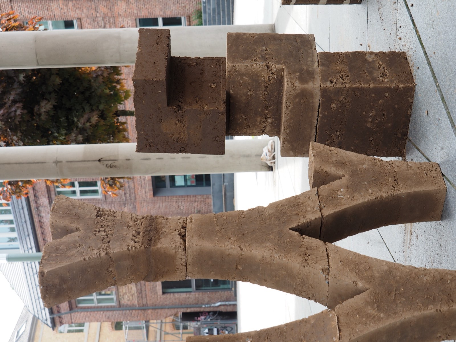 Lehmziegel-Skulpturen im Workshop: zwei geformte Lehmkörper auf Dachterrasse