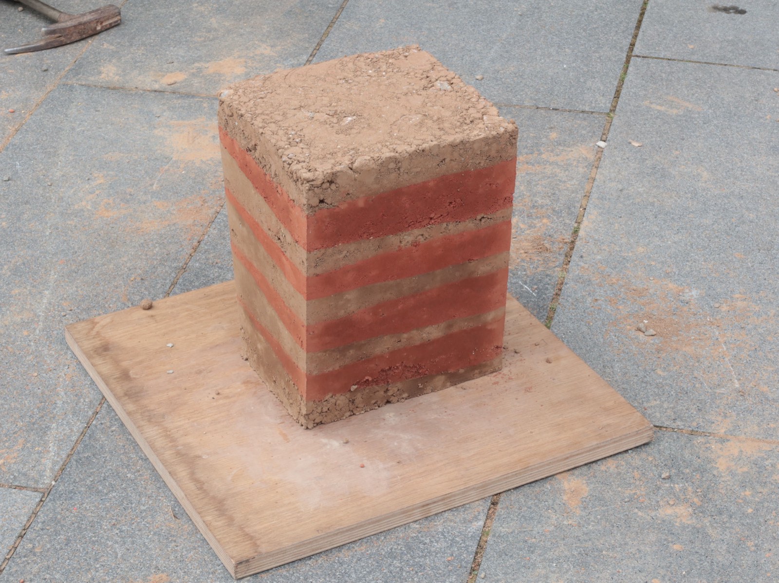 Stampflehm-Workshop: Studierender befüllt Schalung mit Lehmmasse von oben